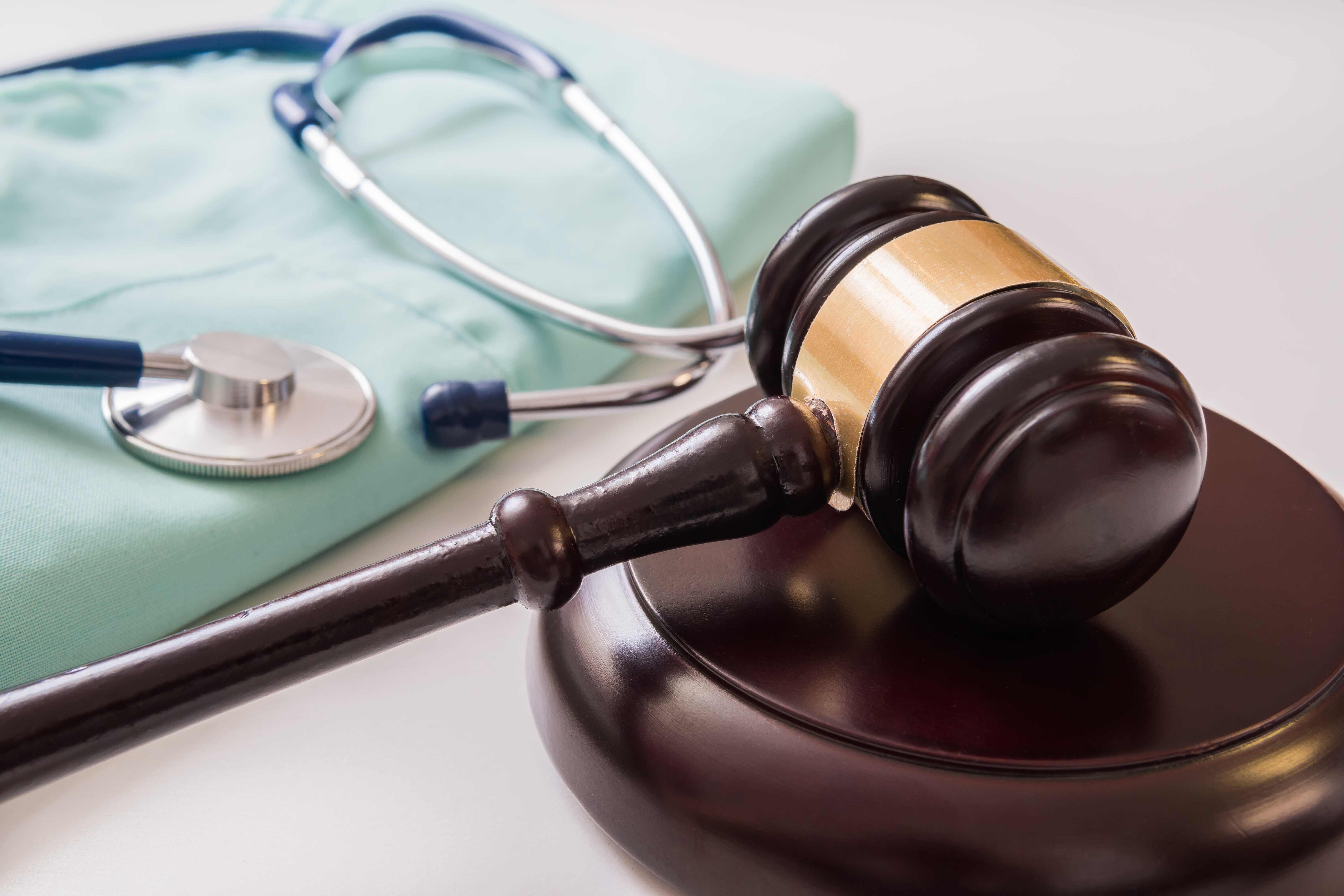 Medical scrubs and stethoscope next to a gavel