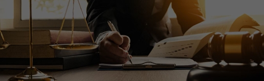 lawyer writing on desk with scales of justice and gavel nearby