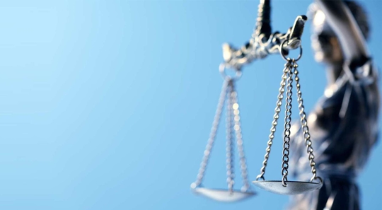 Lady Justice holds out scales on a blue background