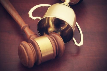 Judge's gavel on a table with a small gold trophy